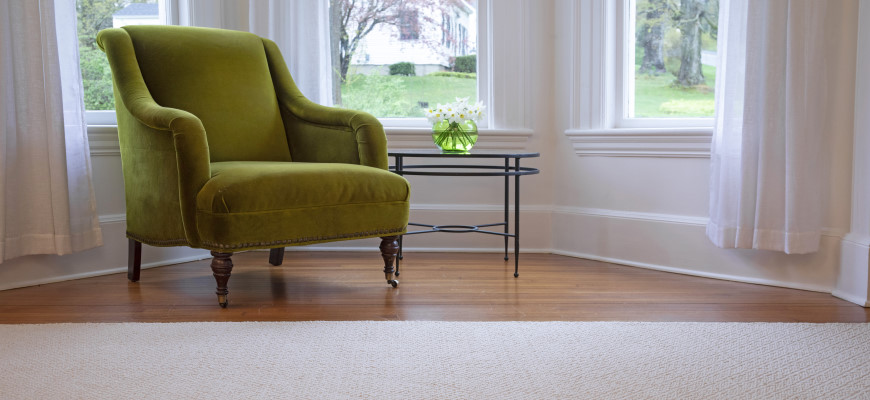 Diamonds organic cotton rug on a dining room floor next to a green velvet chair and windows