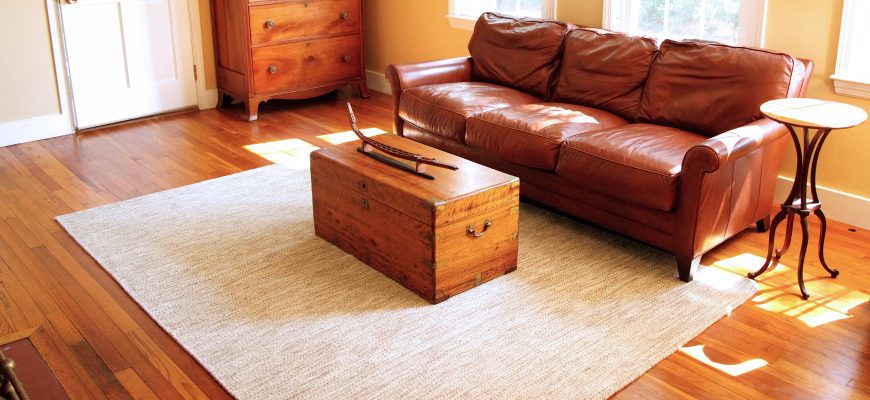Durham 6x9 Thick Woven Wool rug in a living room with a wooden chest and leather couch, banner size
